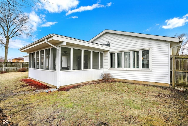 view of side of property with a lawn, fence, and a sunroom