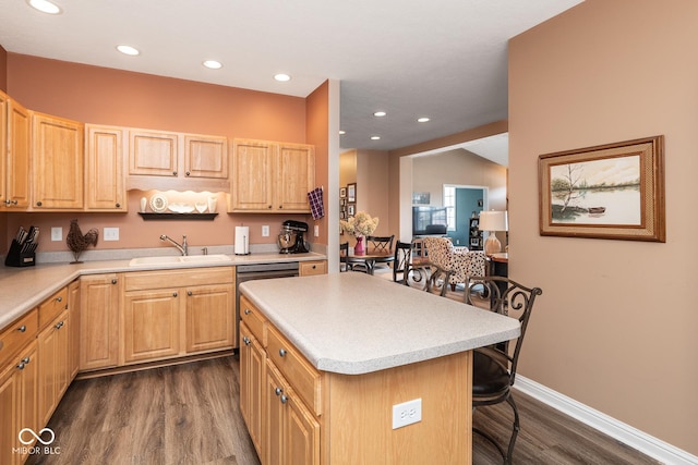 kitchen featuring a breakfast bar area, dark wood finished floors, a sink, and light countertops