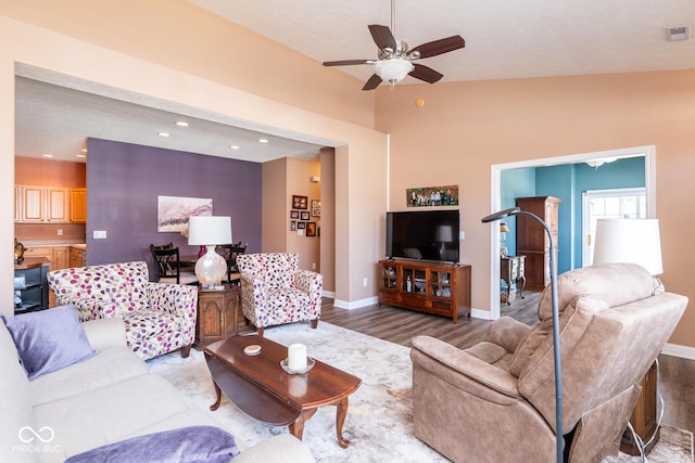 living room with visible vents, ceiling fan, baseboards, and wood finished floors