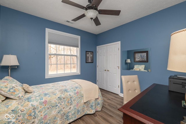 bedroom featuring ceiling fan, a closet, wood finished floors, and visible vents