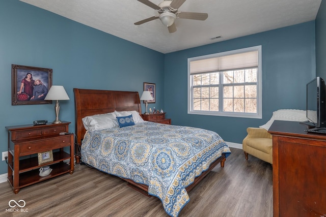 bedroom with visible vents, a ceiling fan, a textured ceiling, wood finished floors, and baseboards