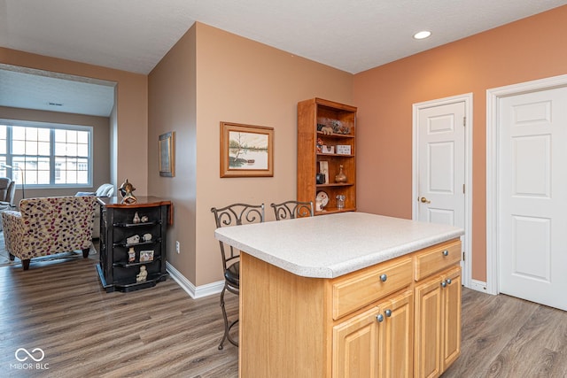 kitchen with a kitchen breakfast bar, wood finished floors, and light countertops