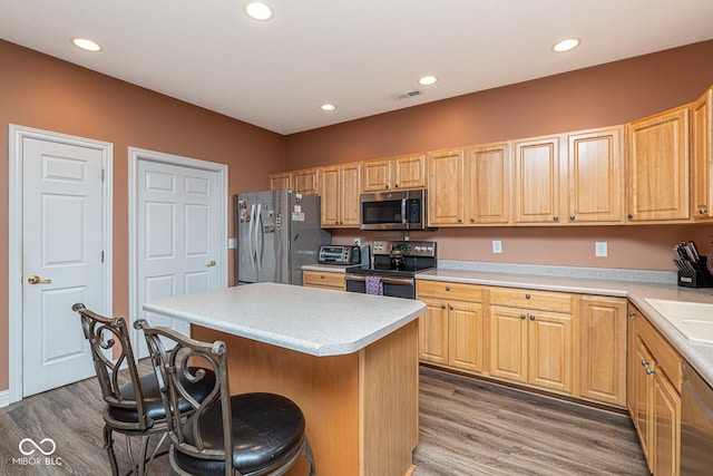 kitchen with dark wood-style floors, visible vents, appliances with stainless steel finishes, and a breakfast bar area