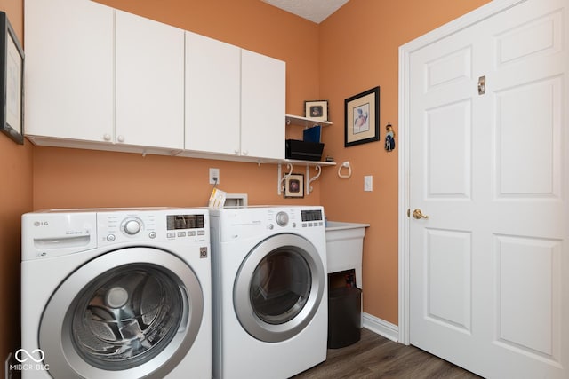 laundry room with dark wood-style floors, washing machine and dryer, cabinet space, and baseboards