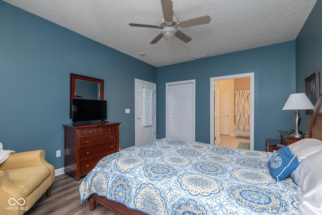 bedroom with a textured ceiling, ceiling fan, connected bathroom, wood finished floors, and visible vents