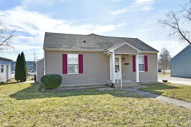 view of front of property featuring a front lawn and a shingled roof