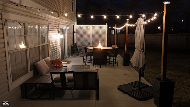 patio at twilight with an outdoor living space with a fire pit and a fenced backyard