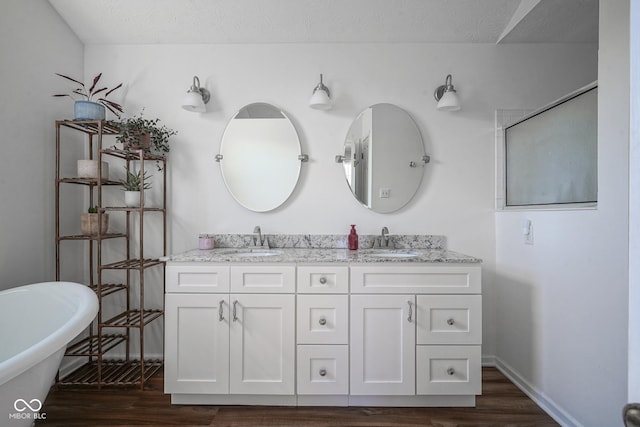 full bath with double vanity, wood finished floors, and a sink