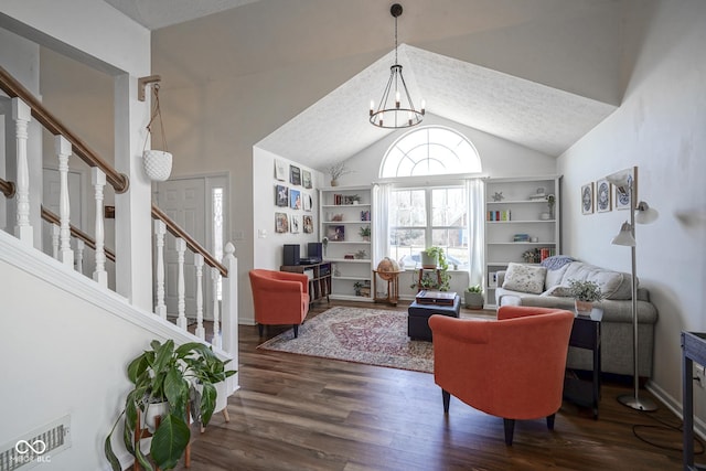 living area featuring wood finished floors, stairs, vaulted ceiling, a textured ceiling, and a chandelier