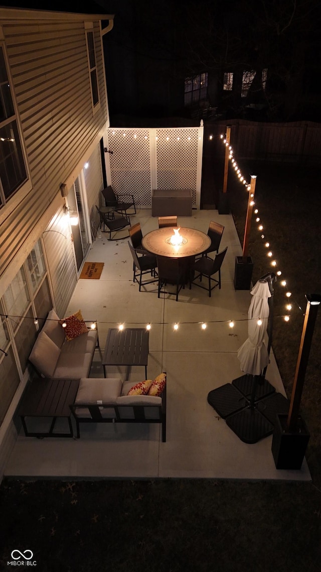 patio at night with an outdoor living space with a fire pit