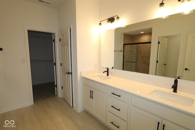 bathroom featuring double vanity, a stall shower, visible vents, and a sink