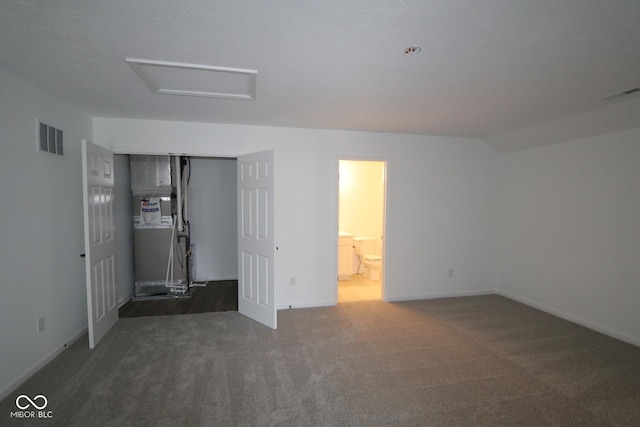 unfurnished bedroom featuring carpet floors, attic access, visible vents, and a closet