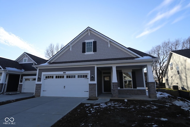 view of front facade featuring a porch, concrete driveway, and stone siding