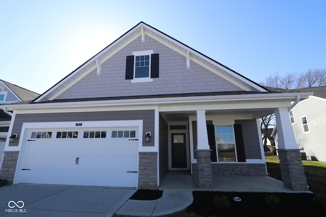 view of front of home featuring stone siding, covered porch, and driveway