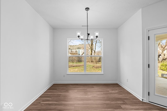 unfurnished dining area featuring baseboards, dark wood-style floors, visible vents, and a chandelier