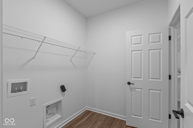 clothes washing area with dark wood-style floors, washer hookup, laundry area, and baseboards