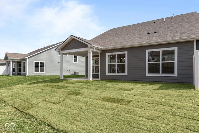 rear view of property featuring central air condition unit, roof with shingles, a patio area, and a yard