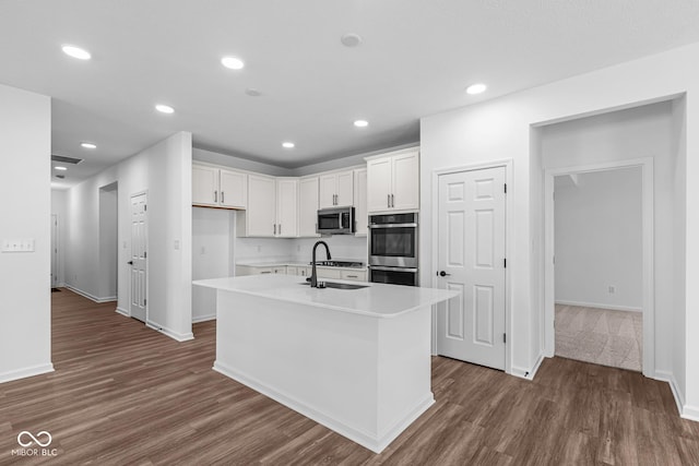 kitchen with light countertops, stainless steel appliances, dark wood-type flooring, a sink, and white cabinets