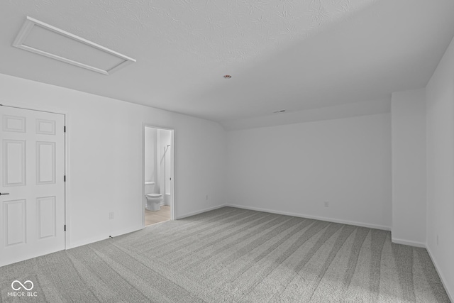 carpeted spare room with baseboards and attic access