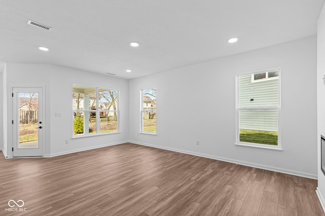 empty room with wood finished floors, a wealth of natural light, recessed lighting, and visible vents
