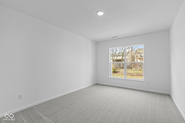 unfurnished room with baseboards, visible vents, and light colored carpet