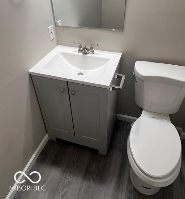 bathroom with toilet, wood finished floors, vanity, and baseboards