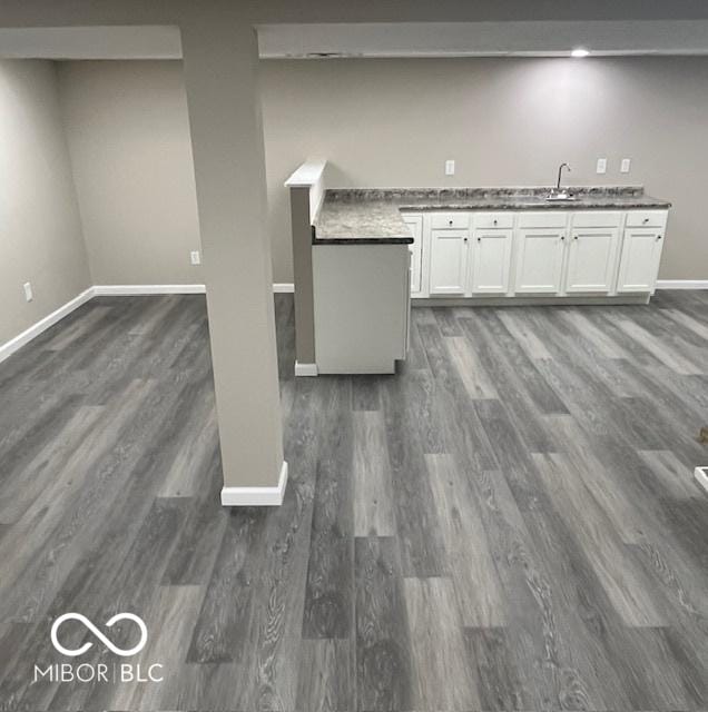 kitchen featuring baseboards, white cabinets, dark countertops, dark wood-style flooring, and a sink