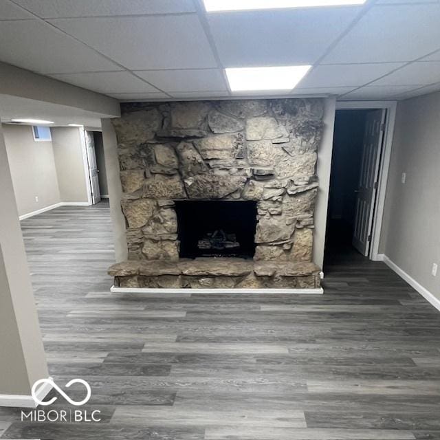 unfurnished living room featuring a paneled ceiling, baseboards, and wood finished floors