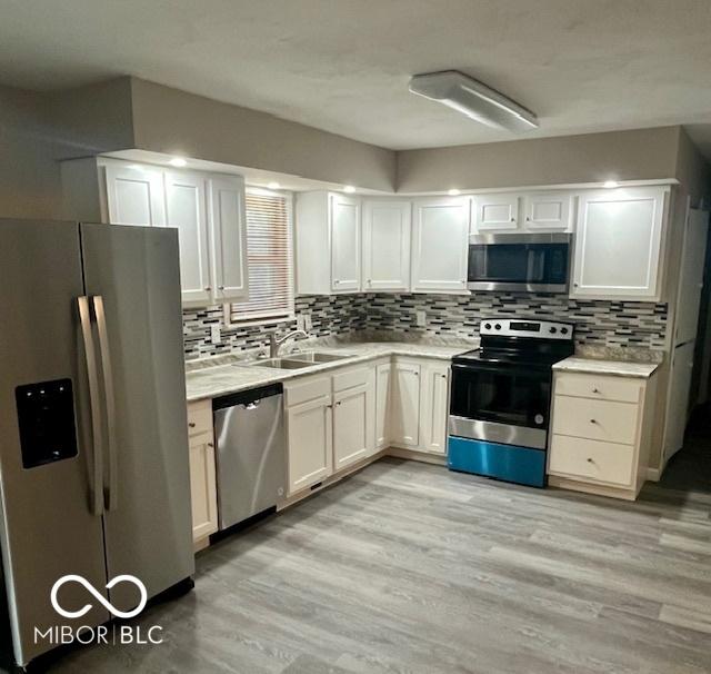 kitchen with a sink, stainless steel appliances, light wood finished floors, and light countertops