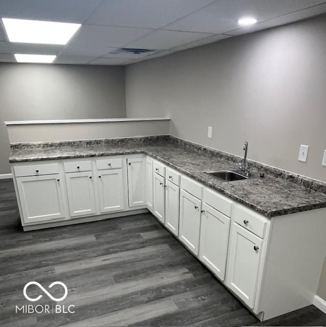 kitchen featuring dark wood-style flooring, white cabinets, a sink, and a peninsula