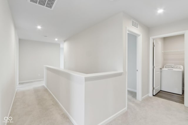 corridor featuring washer / dryer, carpet, visible vents, and an upstairs landing