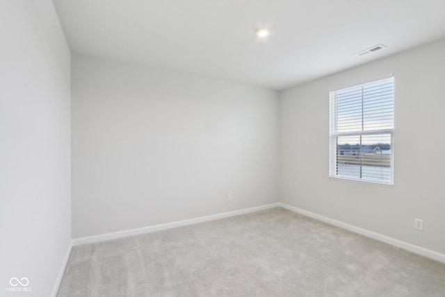 unfurnished room with baseboards, visible vents, and light colored carpet