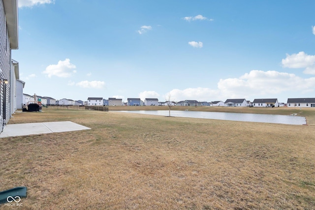 view of yard featuring a patio area, a water view, fence, and a residential view