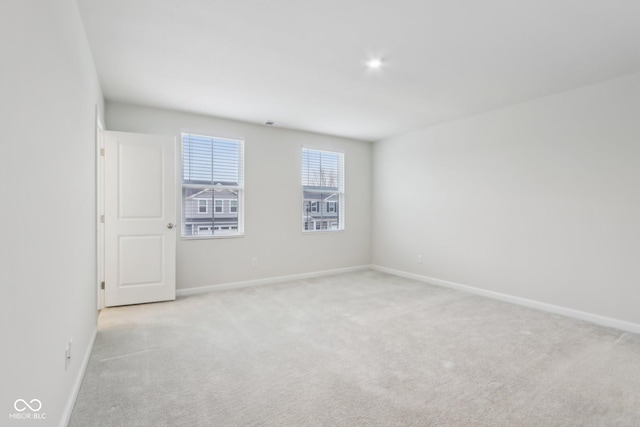 unfurnished room featuring light colored carpet and baseboards