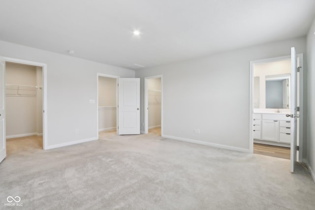 unfurnished bedroom with a spacious closet, a closet, and light colored carpet