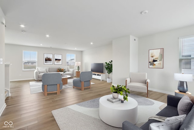 living room featuring light wood finished floors, plenty of natural light, baseboards, and recessed lighting