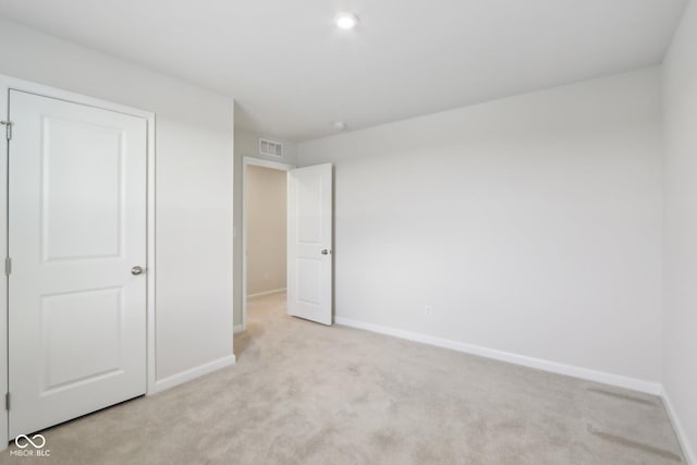 unfurnished bedroom featuring light colored carpet, visible vents, and baseboards