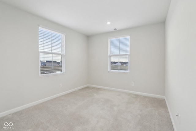 unfurnished room with light carpet, visible vents, and baseboards