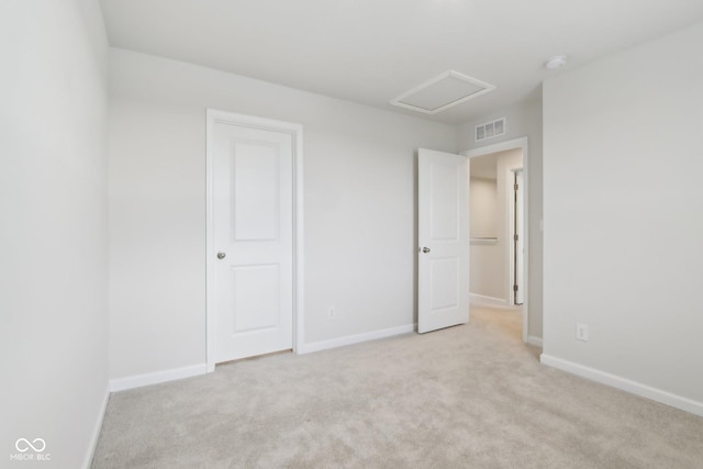 unfurnished bedroom featuring light carpet, baseboards, visible vents, and attic access