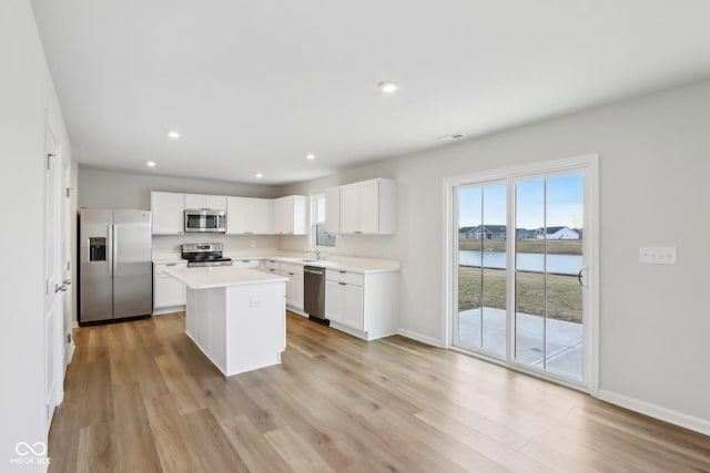 kitchen featuring light wood finished floors, appliances with stainless steel finishes, light countertops, white cabinetry, and a sink