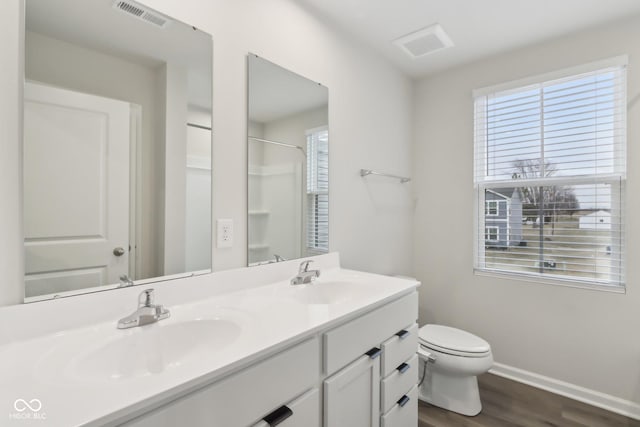 bathroom with toilet, visible vents, a sink, and wood finished floors