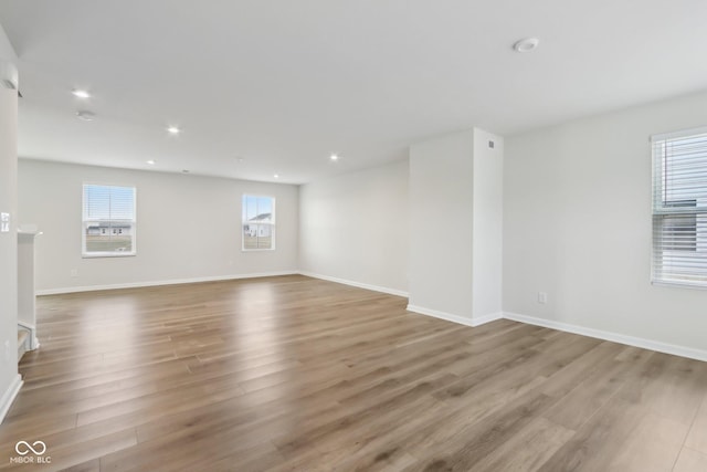 unfurnished living room with baseboards, wood finished floors, and recessed lighting