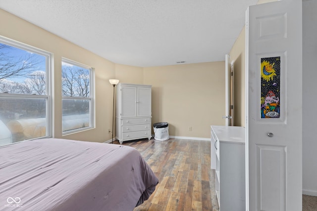 bedroom featuring wood-type flooring, visible vents, a textured ceiling, and baseboards