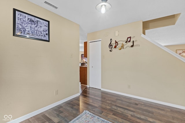 spare room featuring baseboards, visible vents, and dark wood-type flooring