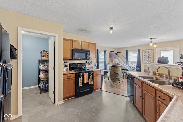 kitchen with a textured ceiling, black appliances, a sink, and light countertops