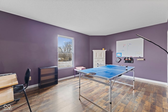 rec room with a textured ceiling, hardwood / wood-style floors, and baseboards