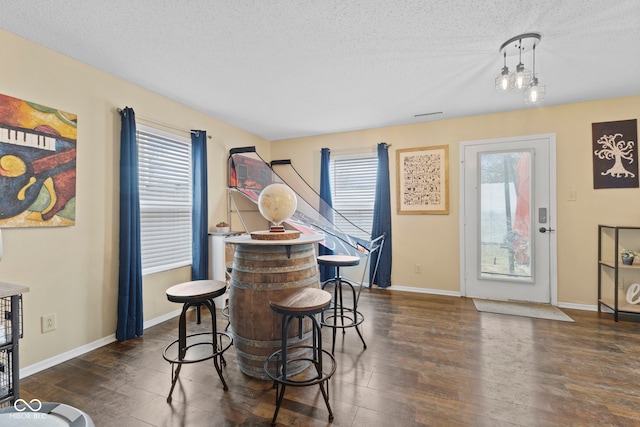 bar featuring baseboards, dark wood finished floors, and a textured ceiling