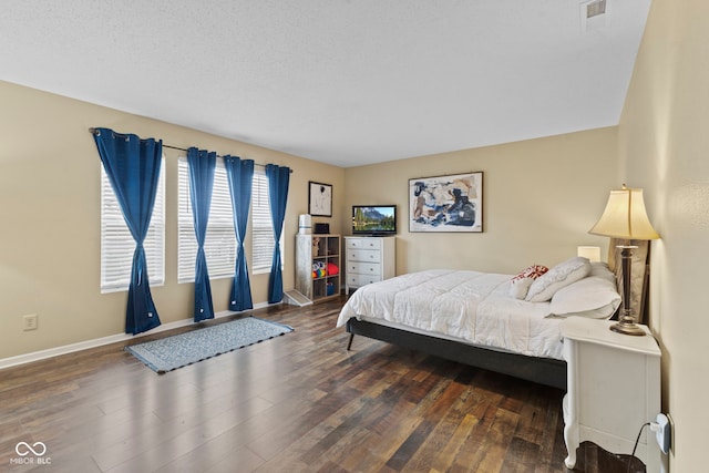 bedroom with visible vents, baseboards, and wood finished floors