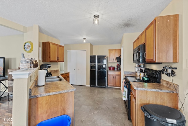 kitchen with black appliances, a textured ceiling, brown cabinets, and a sink