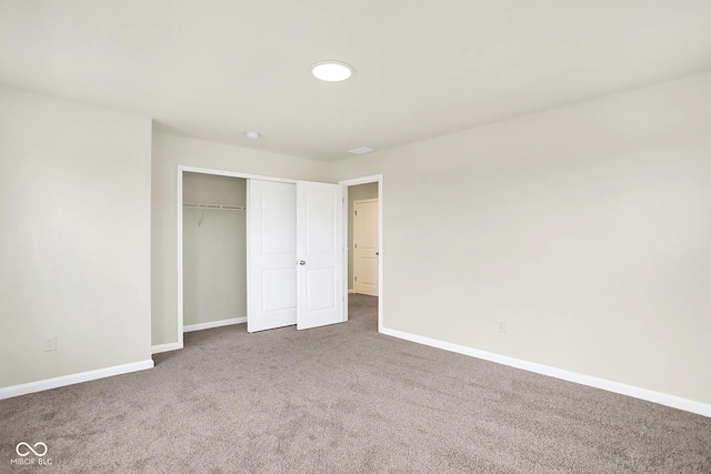 unfurnished bedroom with carpet, a closet, and baseboards